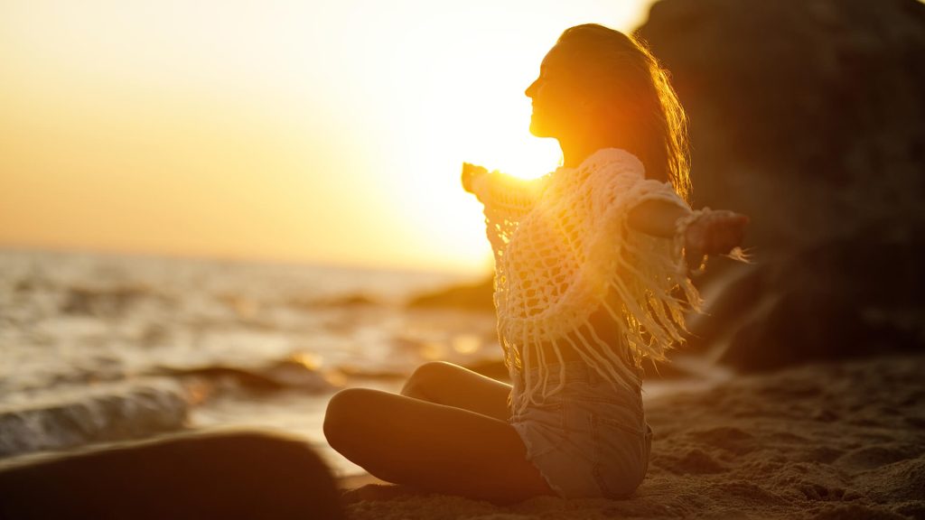 happy woman with arms outstretched relaxing sandy beach enjoying summer sunset