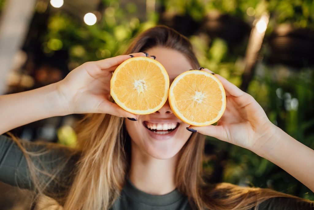 happy young caucasian woman holding fresh oranges front eyes smiling 2